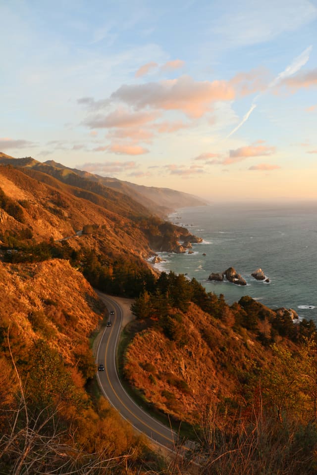 Big Sur coastline at sunset with winding road and warm golden light