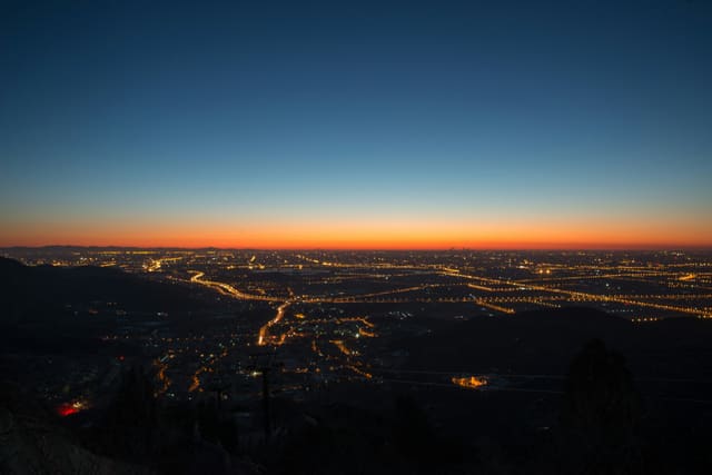 City lights at twilight under a deep blue sky fading to orange at the horizon